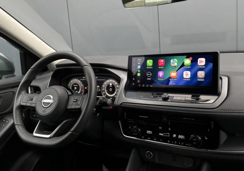 Vue intérieure du tableau de bord et volant noir du Nissan Qashqai 2024 avec écran tactile large et affichage numérique.