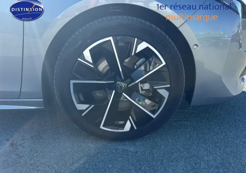 Gros plan sur la roue avant droite avec jante alu noire et argentée d'une Peugeot 508 SW gris artense.