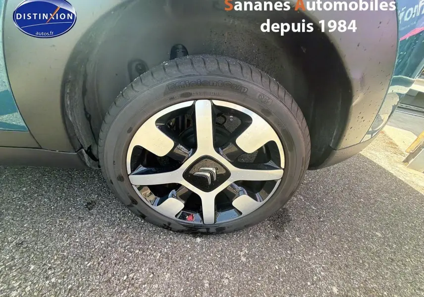 Gros plan sur la roue avant gauche d'une Citroën C4 Cactus bleu métal avec jante alliage bicolore.