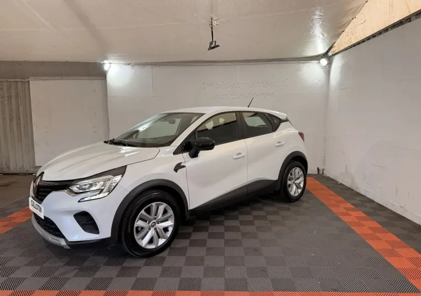 Renault Captur blanc vue 3/4 avant droit dans un garage avec rétroviseurs noirs et jantes argentées.