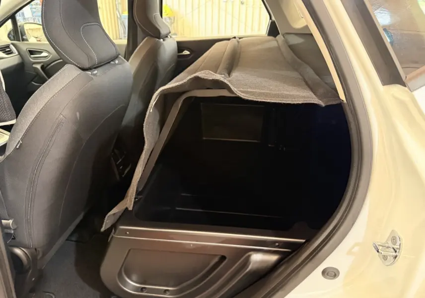 Vue intérieure côté arrière droit du coffre modulable du Renault Captur blanc, montrant le rangement sous plancher.