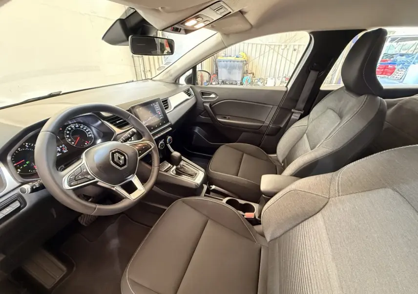 Vue intérieure côté conducteur du Renault Captur Business 2021, sièges tissu gris et noir, tableau de bord avec écran tactile.