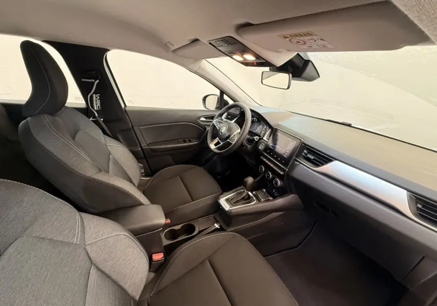 Vue intérieure côté conducteur du Renault Captur Business 2021, montrant sièges tissu gris et tableau de bord moderne.