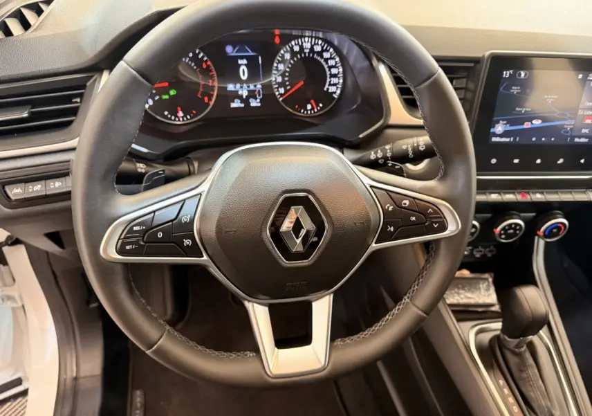 Vue intérieure centrée sur le volant cuir noir du Renault Captur 2021 avec tableau de bord et écran tactile visible.