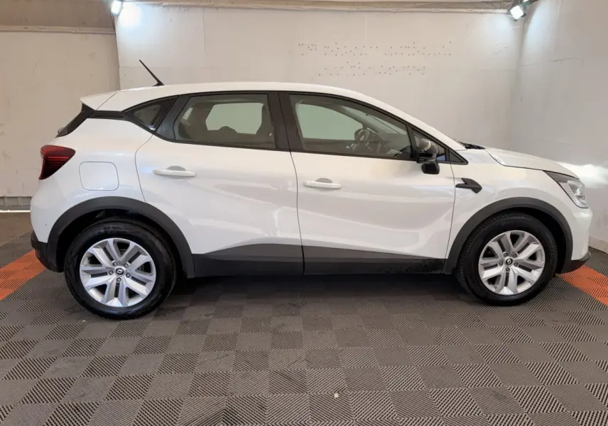Profil côté gauche d'un Renault Captur Business blanc, avec jantes alliage et protections noires sur bas de caisse.