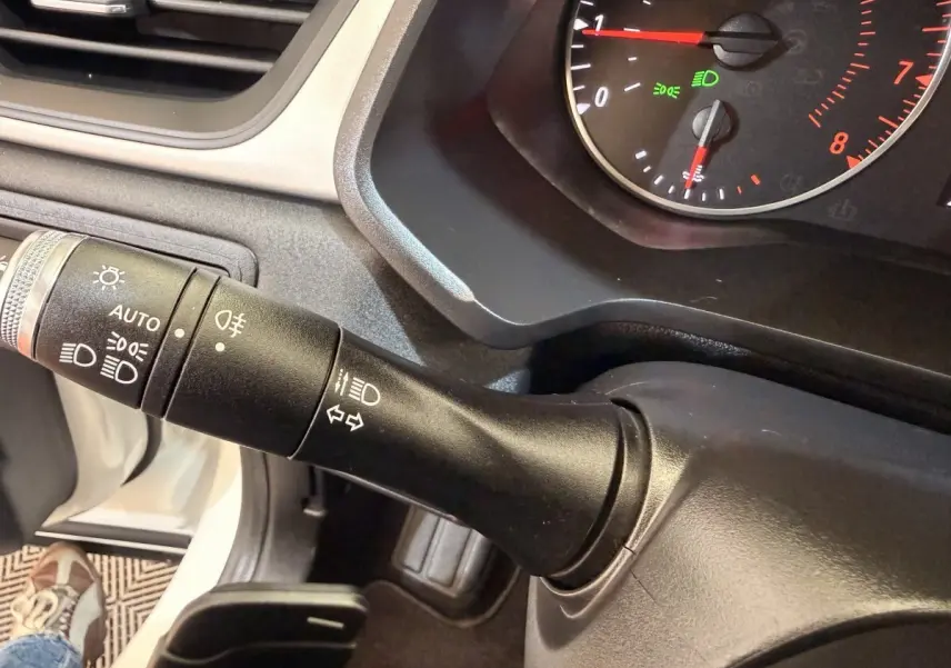 Gros plan sur la commande des phares et clignotants du tableau de bord d'un Renault Captur blanc, version 2021.