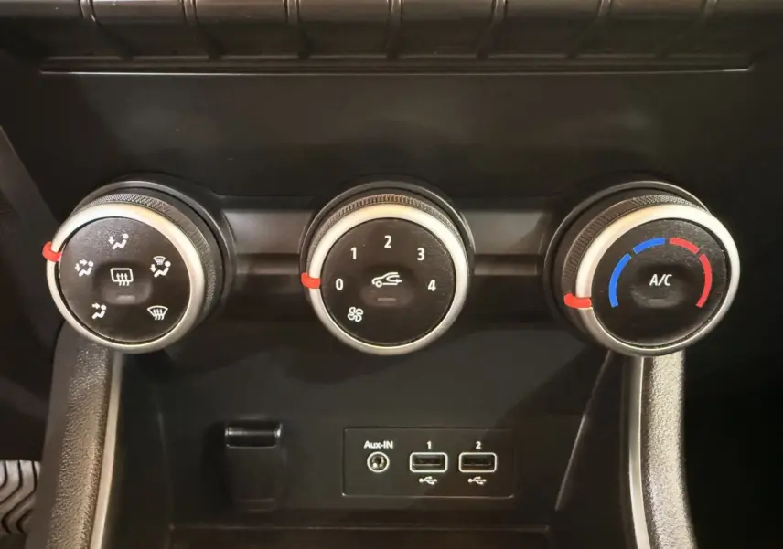 Gros plan sur les commandes de climatisation et les ports USB du tableau de bord noir du Renault Captur blanc 2021.