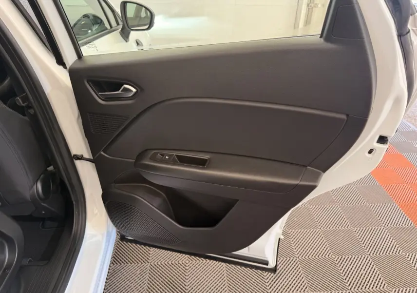 Vue intérieure de la porte arrière droite du Renault Captur blanc, avec panneau noir et commande de vitre électrique.
