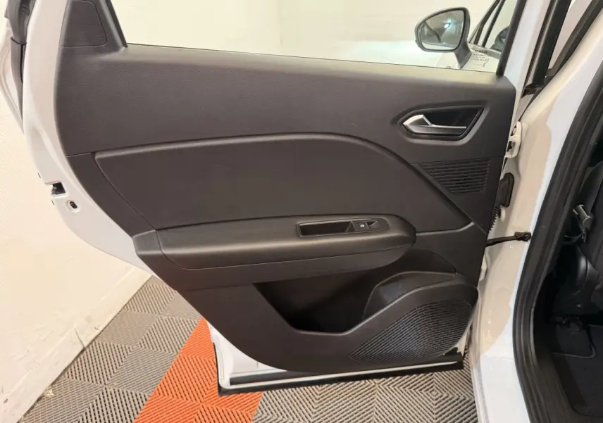 Vue intérieure de la porte arrière droite noire d'un Renault Captur blanc, avec commande de fenêtre et haut-parleur intégré.