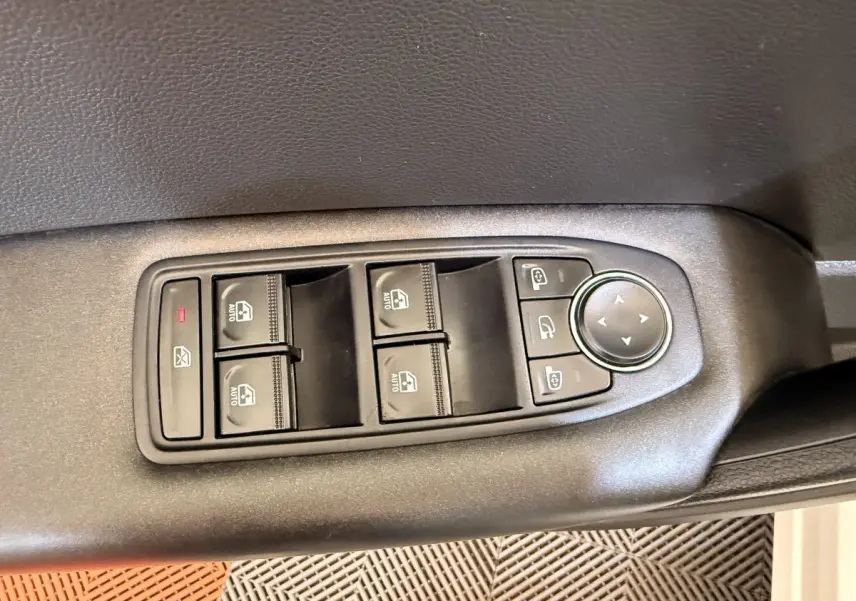 Gros plan sur les commandes de lève-vitres et rétroviseurs sur la porte côté conducteur d’un Renault Captur blanc.
