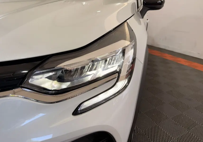 Gros plan sur le phare avant droit blanc du Renault Captur Business TCe 140 EDC FAP 2021 avec rétroviseur noir.