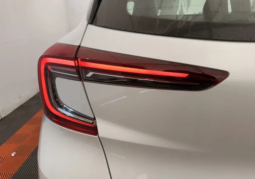 Gros plan sur le feu arrière droit rouge allumé d’un Renault Captur blanc, vue arrière côté droit.
