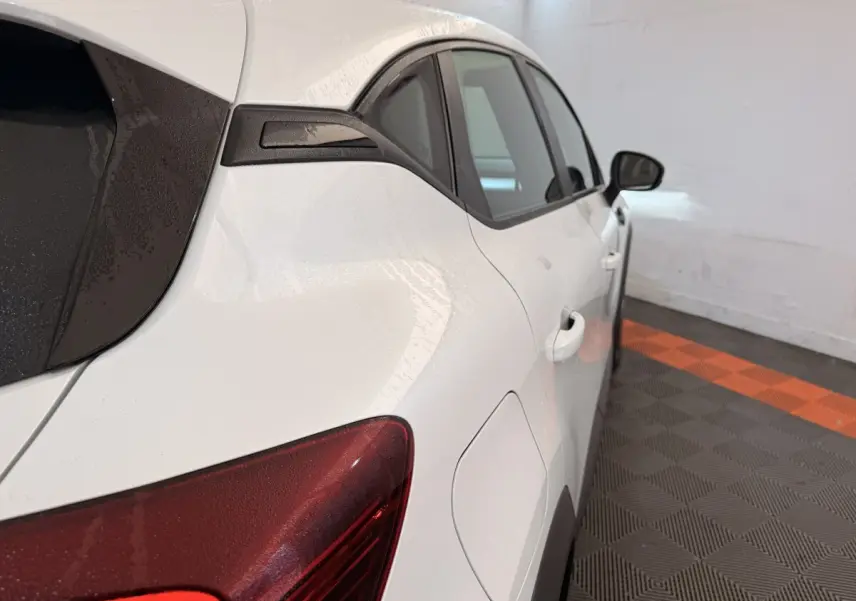 Vue arrière côté droit d’un Renault Captur blanc avec feux arrière rouges et vitres teintées dans un garage.