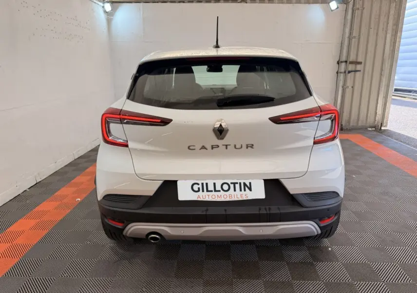 Vue arrière d’un Renault Captur blanc 2021 avec feux LED et logo central dans un garage éclairé.