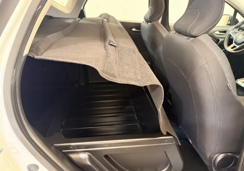 Vue intérieure côté gauche du coffre ouvert du Renault Captur blanc, avec banquette arrière et sièges avant visibles.