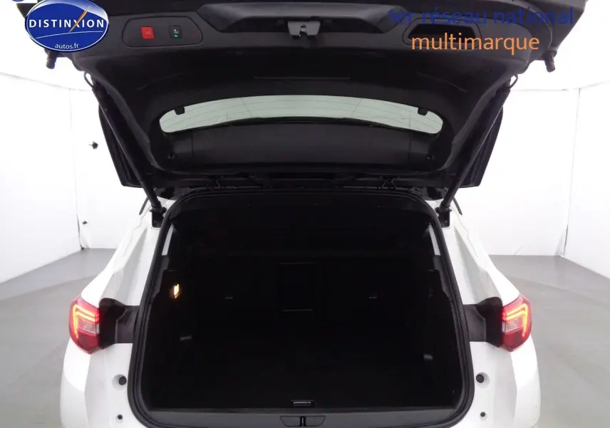 Vue arrière d'un Opel Grandland X blanc nacré avec hayon ouvert dévoilant un coffre spacieux et éclairé.