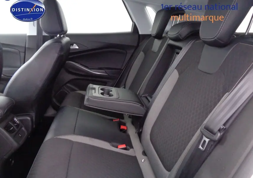 Vue intérieure sur les sièges arrière en tissu noir et gris avec accoudoir central baissé de l'Opel Grandland X blanc nacré.