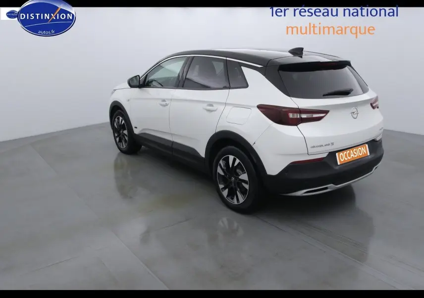 Vue 3/4 arrière droite d'un Opel Grandland X blanc nacré avec toit noir et jantes alliage noires.