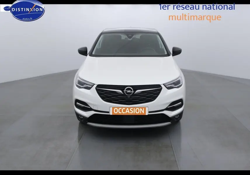 Vue frontale d'un Opel Grandland X blanc nacré avec calandre noire et phares LED dans un studio lumineux.