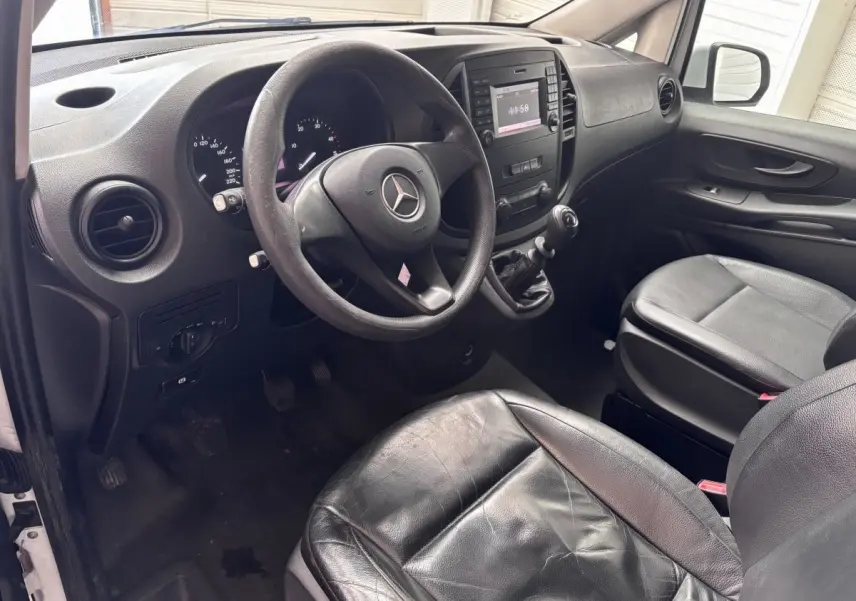 Vue intérieure côté conducteur du Mercedes Vito 111 CDI 2016, volant cuir, sièges noirs et tableau de bord avec écran central.