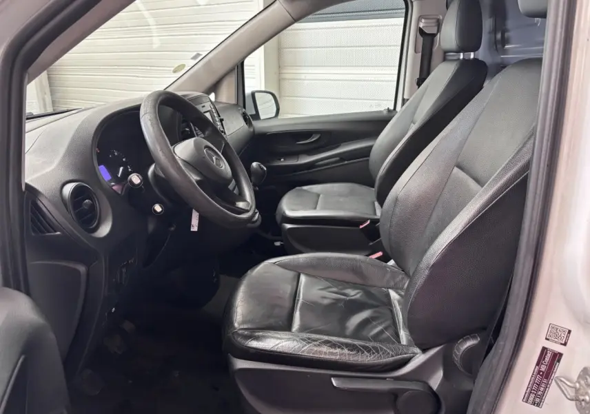 Vue intérieure côté conducteur du Mercedes Vito blanc 2016, sièges en cuir noir et tableau de bord visible.