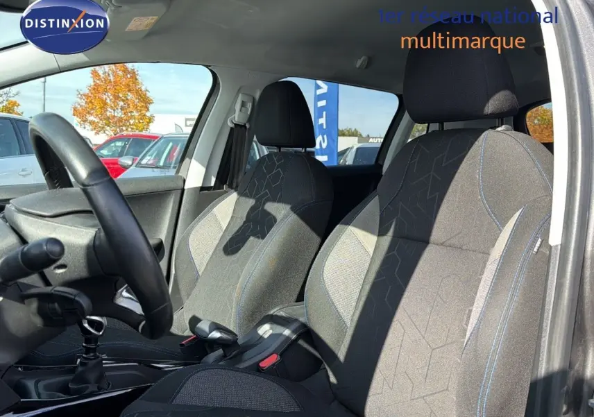 Intérieur du Peugeot 2008 gris platinium, vue côté gauche montrant les sièges avant en tissu noir avec surpiqûres bleues.