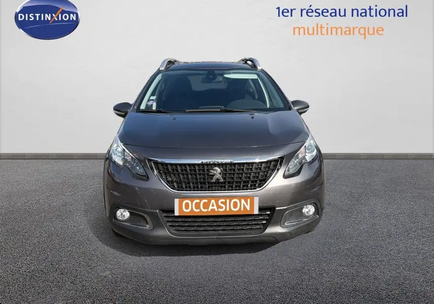Vue frontale d'un Peugeot 2008 gris platinium 2019 avec calandre noire et phares allumés.