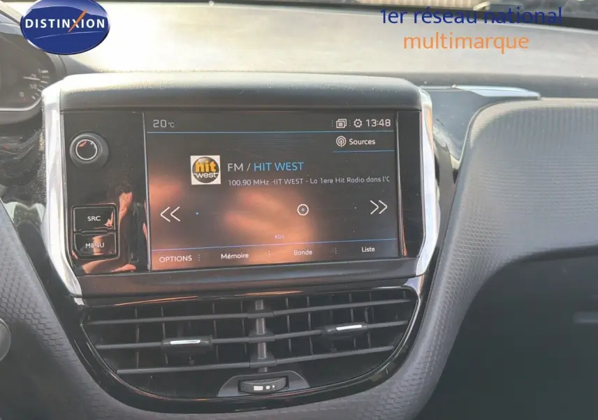 Tableau de bord du Peugeot 2008 gris platinium, vue centrée sur l'écran tactile multimédia affichant une radio FM.