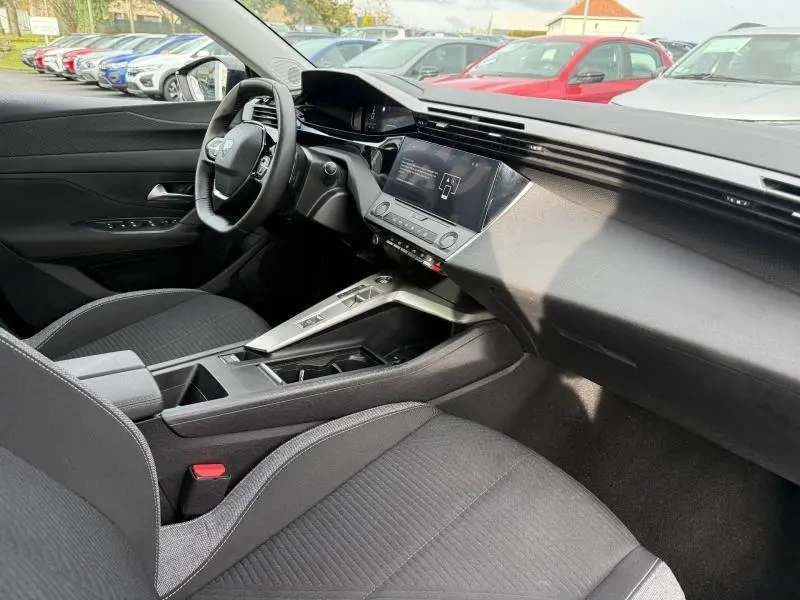 Intérieur de la Peugeot 308 2024 en vue côté conducteur, avec tableau de bord moderne et sellerie noire.