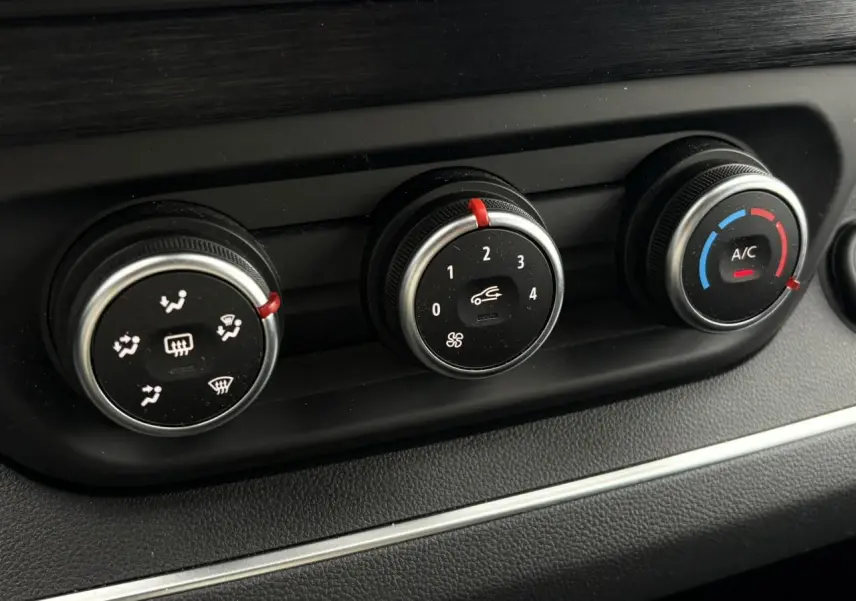 Gros plan sur les commandes de climatisation du Nissan Primastar gris Comète, boutons ronds avec réglages ventilation et A/C.