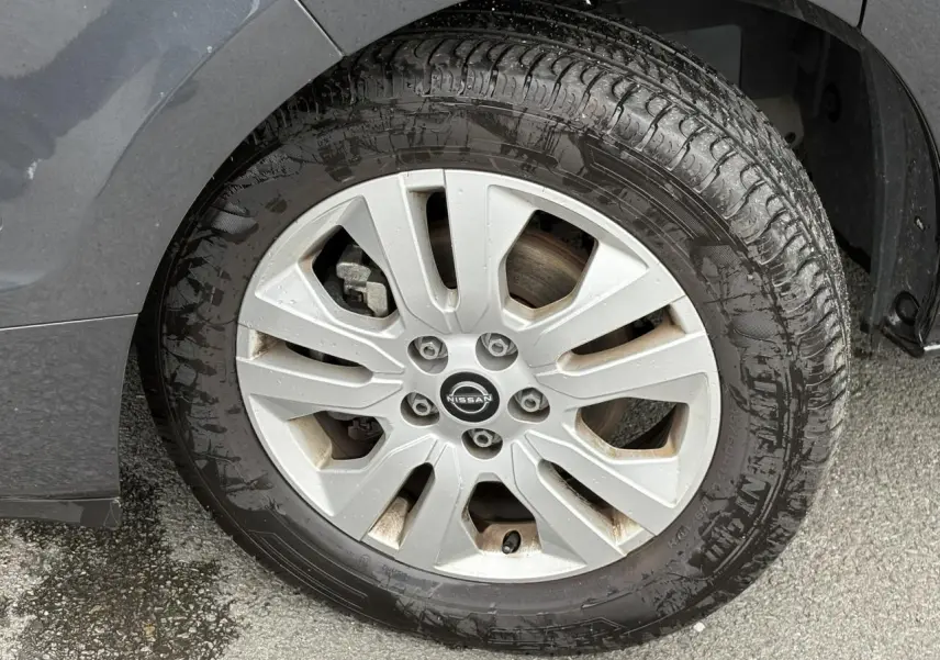 Gros plan sur la jante alliage 17 pouces grise d’un Nissan Primastar gris Comète, avec pneu humide et logo central Nissan.