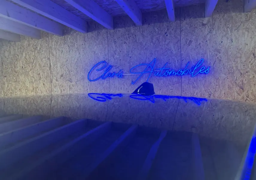Je ne vois pas de véhicule sur cette image, seulement un mur en bois avec un néon bleu indiquant "Claris Automobiles".
