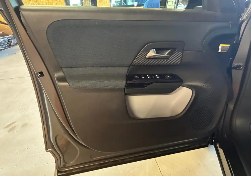 Vue intérieure de la porte arrière gauche grise du Citroën C5 Aircross 1.2 Hybride 145 Plus avec commandes de vitres et haut-parleur intégré.