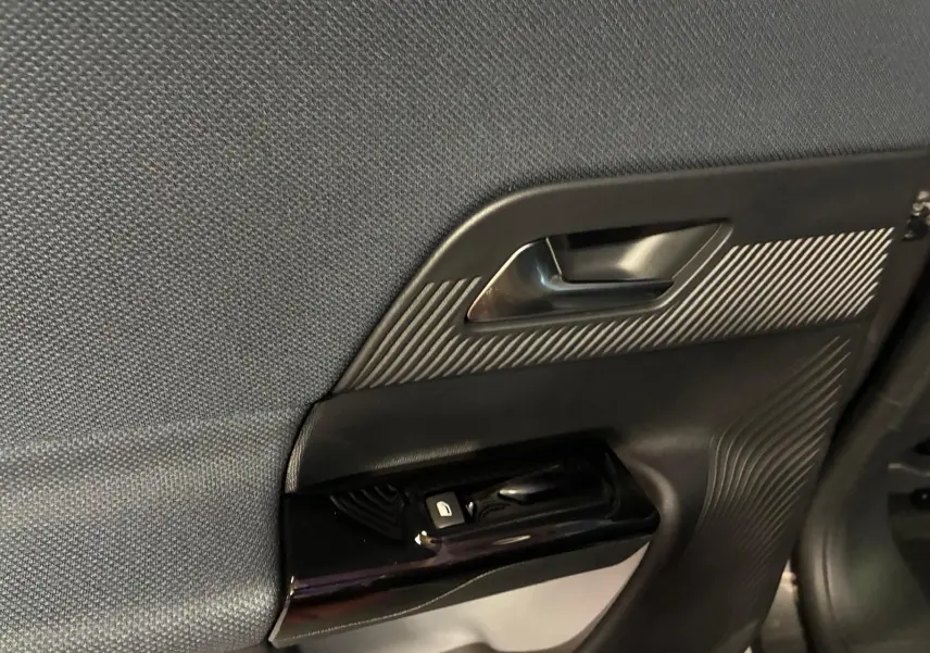 Détail de la porte intérieure côté gauche du Citroën C5 Aircross gris, avec poignée et commandes de vitre.