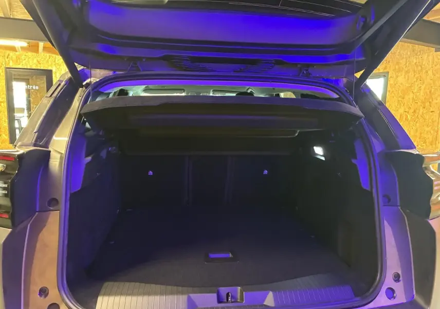 Coffre ouvert vu de l'arrière d'un Citroën C5 Aircross gris, intérieur spacieux avec éclairage LED bleu.