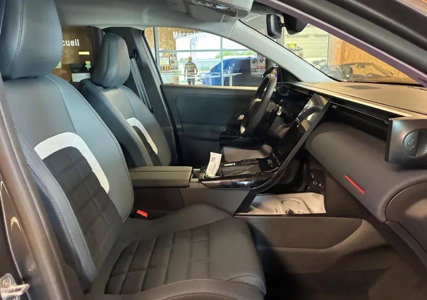 Vue intérieure côté conducteur du Citroën C5 Aircross 1.2 Hybride 145 Plus 2026 avec sièges tissu noir et tableau de bord moderne.