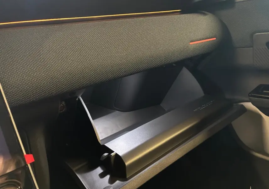 Gros plan sur la boîte à gants ouverte côté passager du Citroën C5 Aircross gris, intérieur tissu noir.