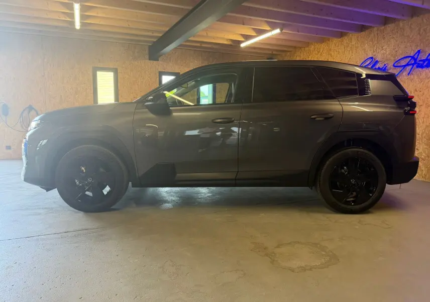 Vue de profil côté gauche du Citroën C5 Aircross gris 2026 avec jantes noires et toit noir en intérieur.