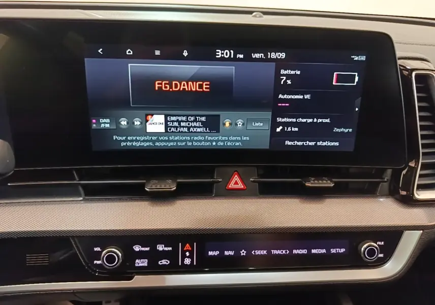 Tableau de bord du Kia Sportage 2022 avec écran tactile 12,3 pouces affichant radio et informations batterie.