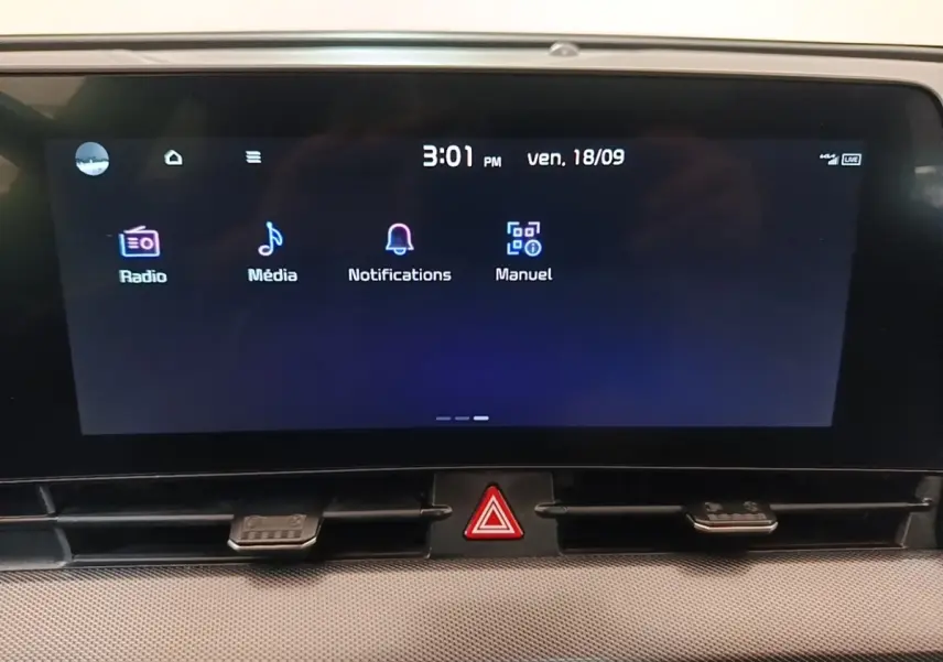 Écran tactile central du tableau de bord du Kia Sportage gris clair, affichant les menus Radio, Média, Notifications et Manuel.