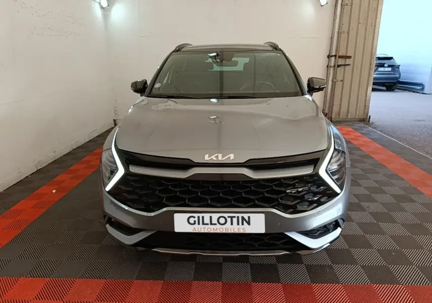 Vue avant d'un KIA Sportage gris clair avec phares LED en forme de C et calandre noire hexagonale.
