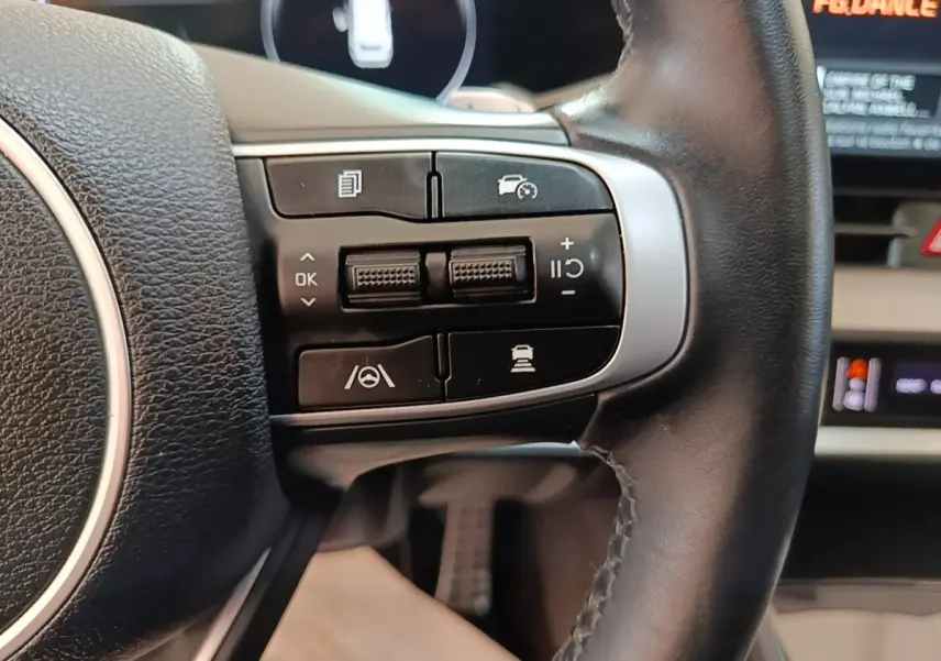 Gros plan sur les commandes de régulateur de vitesse au volant cuir noir du Kia Sportage hybride rechargeable 2022.