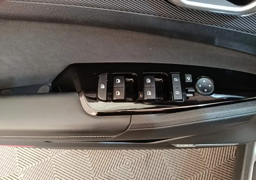 Vue rapprochée du panneau de commandes des vitres côté gauche en plastique noir brillant sur porte intérieure grise du Kia Sportage 2022.