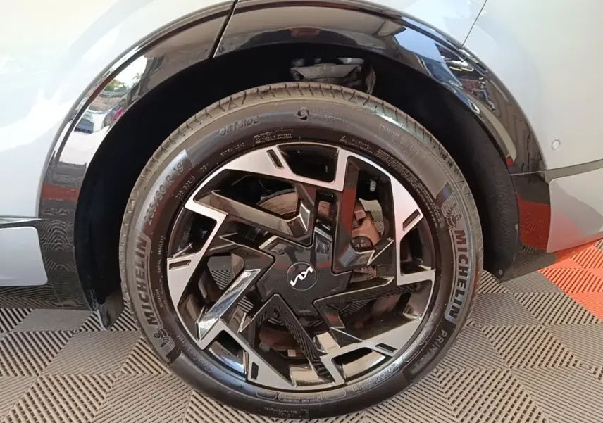 Gros plan sur la roue avant droite gris clair du KIA SPORTAGE 2022 avec jante noire et argentée au design géométrique.