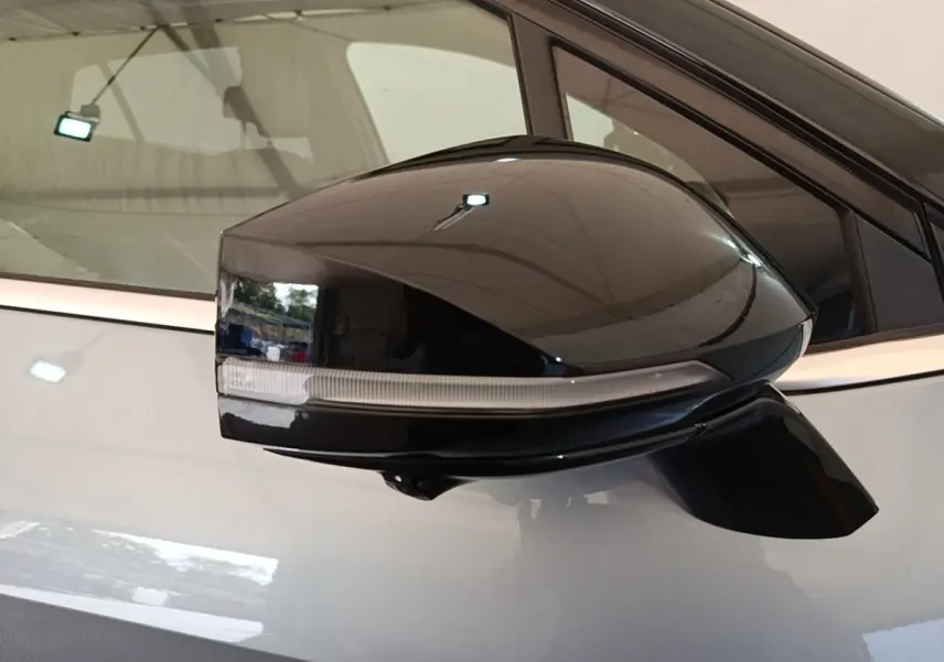 Rétroviseur noir côté gauche d’un KIA Sportage gris clair 2022 avec clignotant intégré, vue rapprochée.