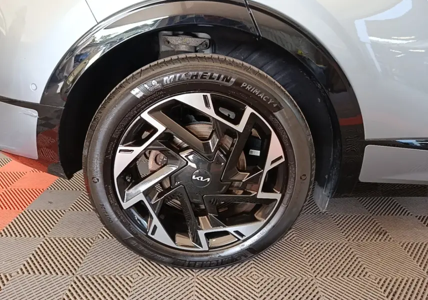 Gros plan sur la roue avant droite du Kia Sportage gris clair 2022 avec jante noire et argentée au design moderne.