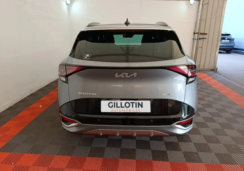 Vue arrière d'un KIA Sportage gris clair 2022 avec logo et feux LED distinctifs dans un garage.