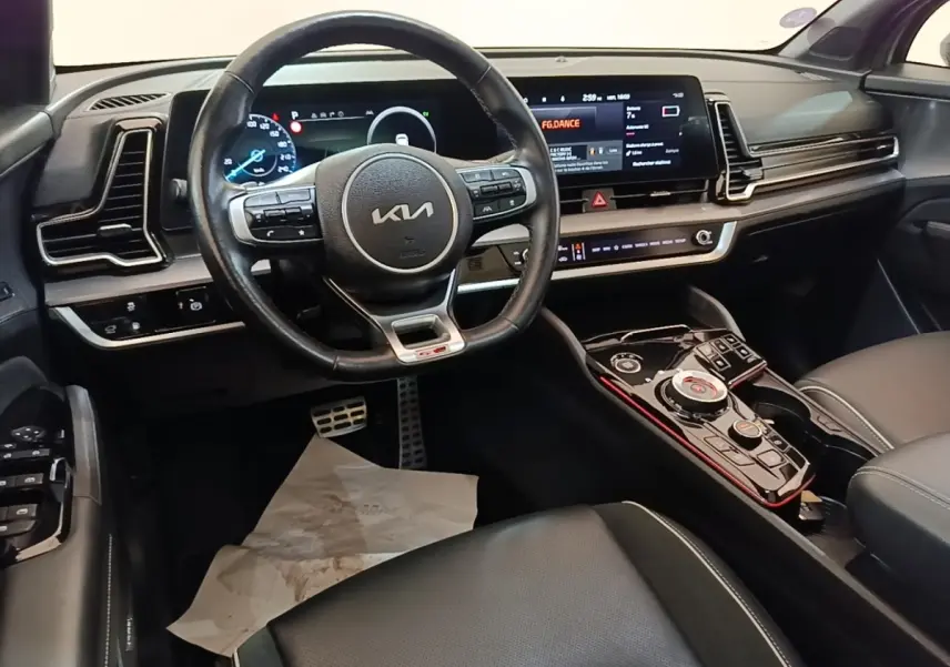 Vue intérieure du poste de conduite du Kia Sportage gris clair 2022, avec volant cuir multifonctions et écran tactile large.