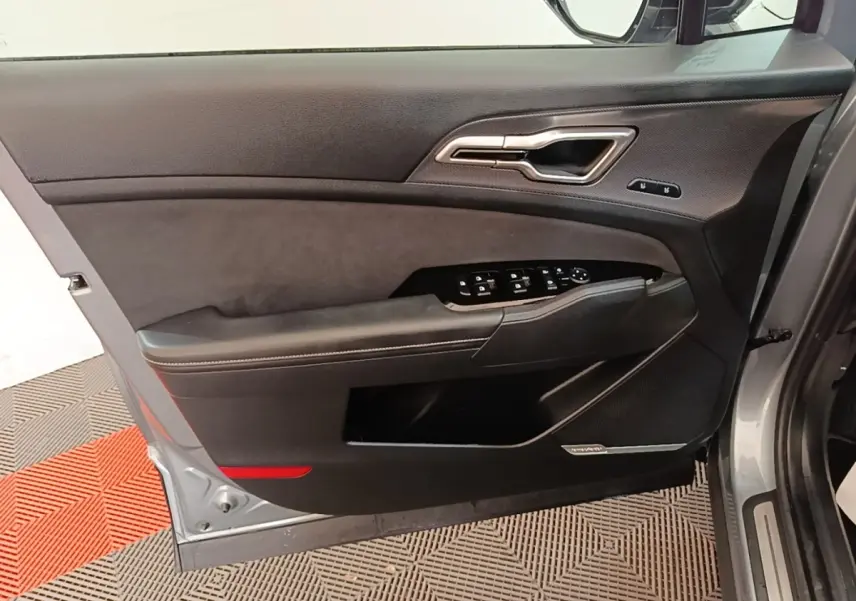 Vue intérieure côté gauche de la porte avant gris clair du Kia Sportage avec commandes électriques et insert noir.