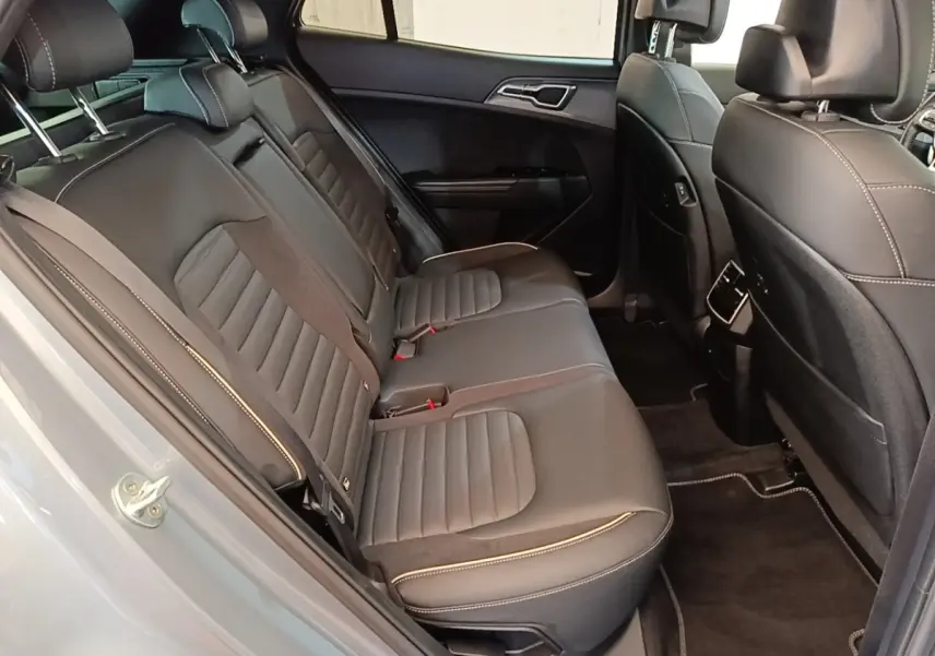 Vue intérieure côté gauche des sièges arrière en cuir noir du Kia Sportage gris clair, avec surpiqûres contrastantes visibles.